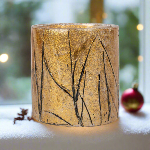 Decorative glass candle holder with leaf pattern on a white background