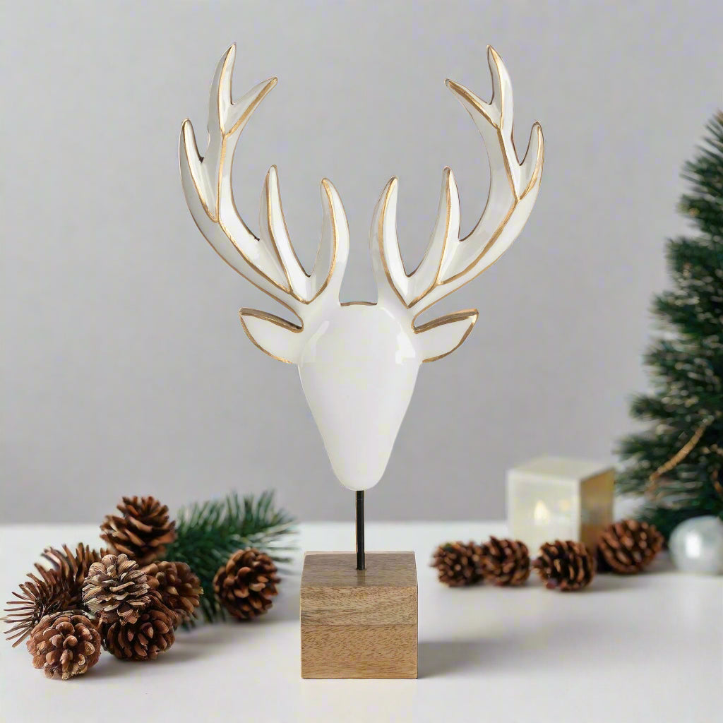 Decorative deer head sculpture with white antlers and a wooden base on a white background