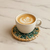 White cup of coffee with latte art on a textured coaster