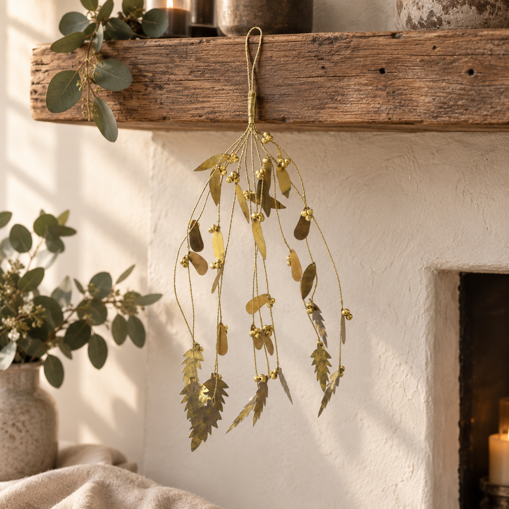 Amelie antique brass mistletoe decoration hanging from an aged oak mantel