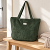 De La Mur Tree dark green corduroy shopper bag on a pale oak bench
