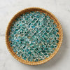 Round woven tray with fish scale pattern on a textured surface