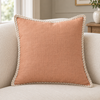 Helbe terracotta linen cushion with cream stitched edging on an ivory upholstered sofa