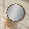 Round antique gold wall mirror styled above a marble console table in a neutral interior