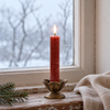 Macon dark red rustic dinner candle glowing on a weathered windowsill