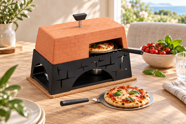 Milan Mini Pizza Oven with terracotta cover and black stand, styled with miniature pizzas on a sunlit oak dining table