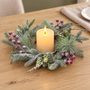 Winterwood Snowy Berry Candle Ring with frosted pine, red berries and pinecones around an ivory candle on an oak table