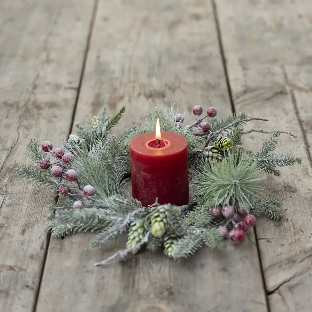 Original supplier photograph of the snowy pine and red berry candle ring, shown with a red candle